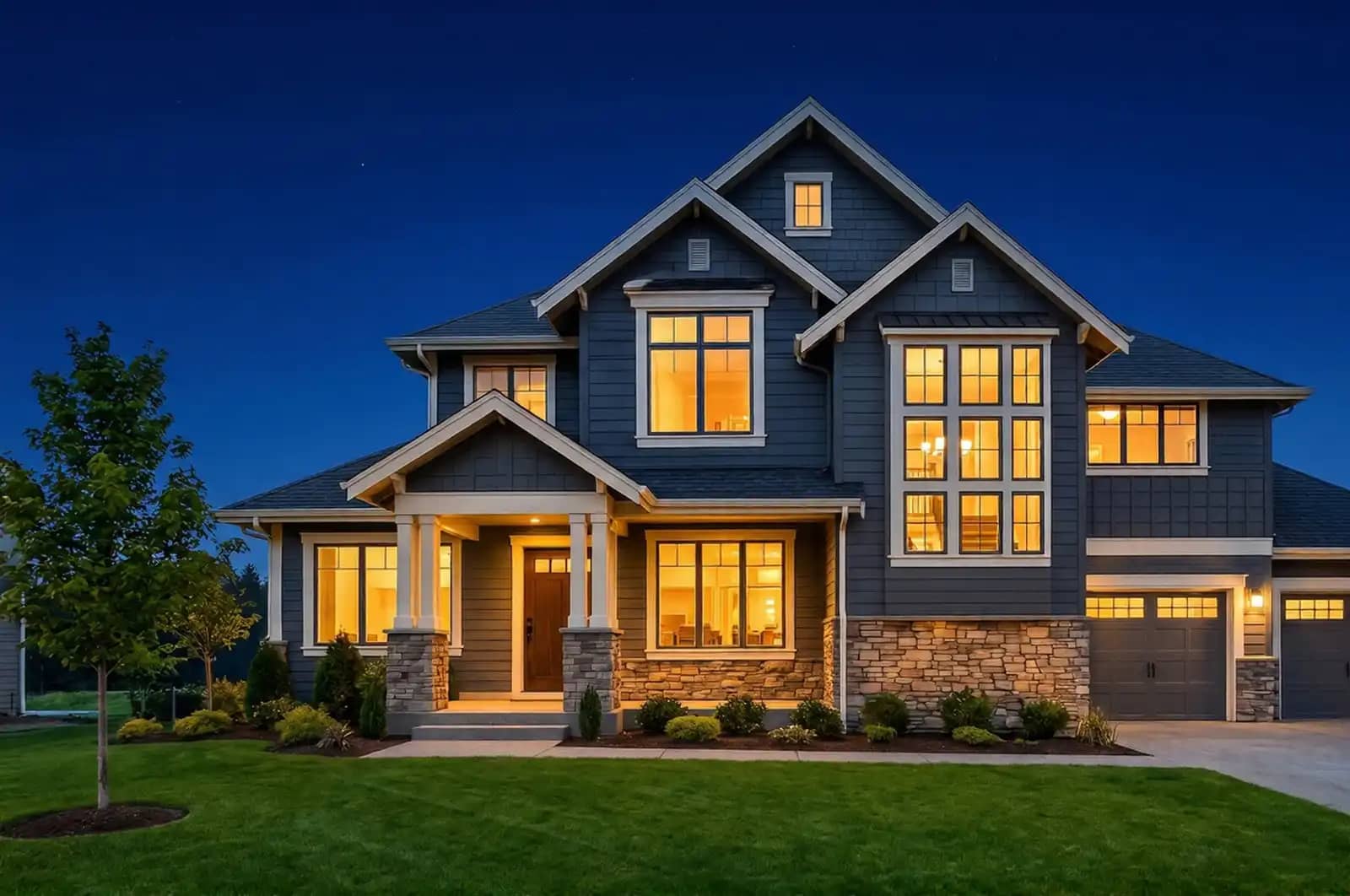 Modern two-story home at twilight with warm window lighting